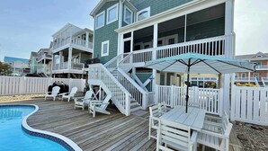 A multi-story residential building with a pool, outdoor seating, and a covered patio area.