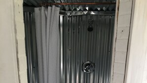A compact bathroom with a shower, toilet, and a small step leading to the shower.