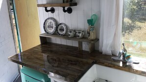 A kitchen with a wooden countertop, a sink, and a window with a view of trees.