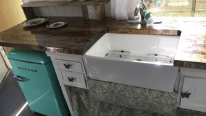 A kitchen with a sink, two drawers, a patterned tablecloth, and a teal appliance.
