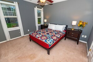 A bedroom with a bed, nightstands, a lamp, and a vase of flowers.
