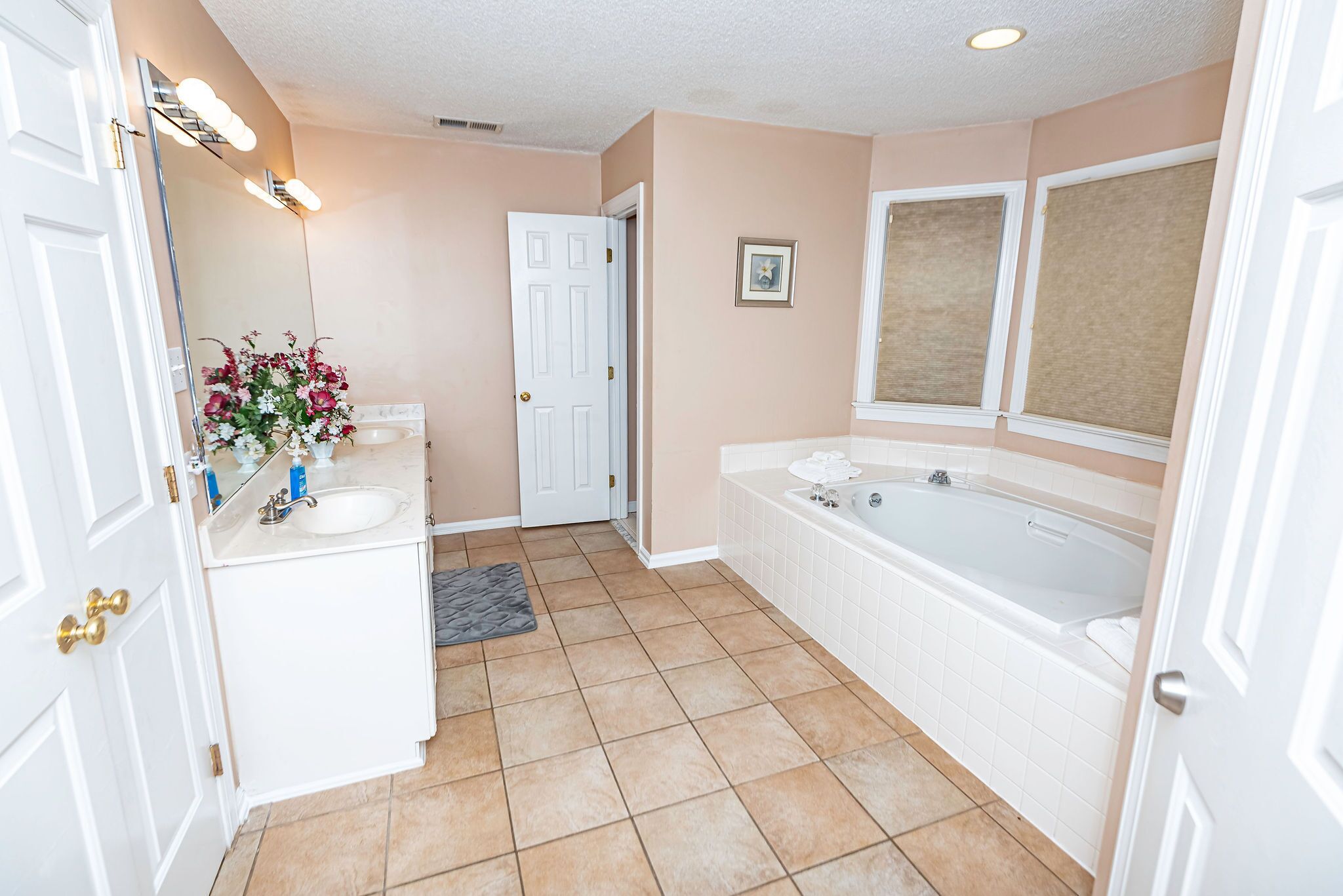 A bathroom with a sink, mirror, vanity, and bathtub.