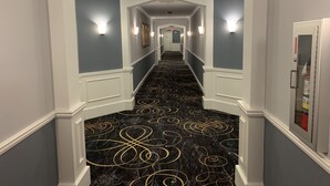 A hallway with a black marble floor featuring gold swirls, white wainscoting, and light blue walls.