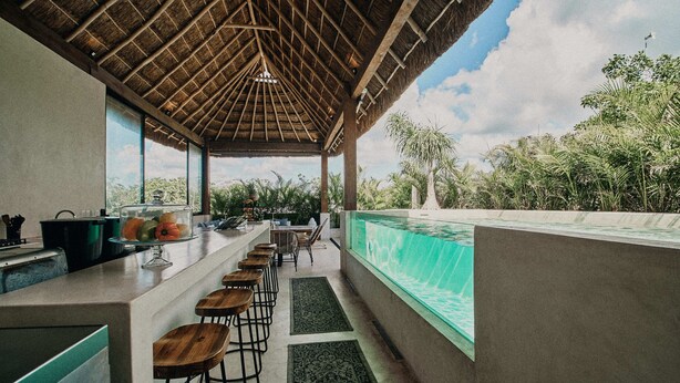 Eine moderne Küche mit Barbereich, Pool und Blick auf die umliegende Grünfläche.
