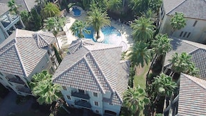 Un quartier résidentiel comprenant plusieurs maisons, une piscine et des palmiers.