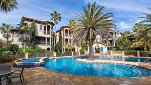 Une piscine entourée de palmiers et un bâtiment doté de nombreux balcons.