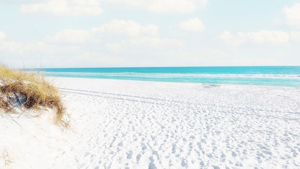 Une plage de sable blanc, sous un ciel bleu azur.