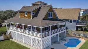 Une maison à deux étages dotée d’une terrasse couverte et d’une piscine.
