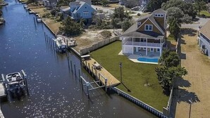 Un quartier résidentiel avec une maison dotée d’un grand jardin à l’avant et d’une piscine.