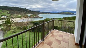 A balcony with a view of a coastal landscape, including a beach and mountains. - Stunning ocean views, Sunsets and just 30 seconds from the Beach! (GA)