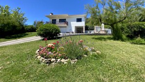 A two-story house with a well-maintained lawn and flower beds. - Stunning ocean views, Sunsets and just 30 seconds from the Beach! (GA)