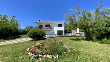 Une maison à deux étages avec une pelouse bien entretenue et des parterres de fleurs.