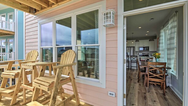 A wooden deck with Adirondack chairs, a kitchen with modern appliances, and a large window overlooking the deck. - 'The Tipsy Flamingo' ~ Incredible Salt Marsh Views (Atlantic Beach)