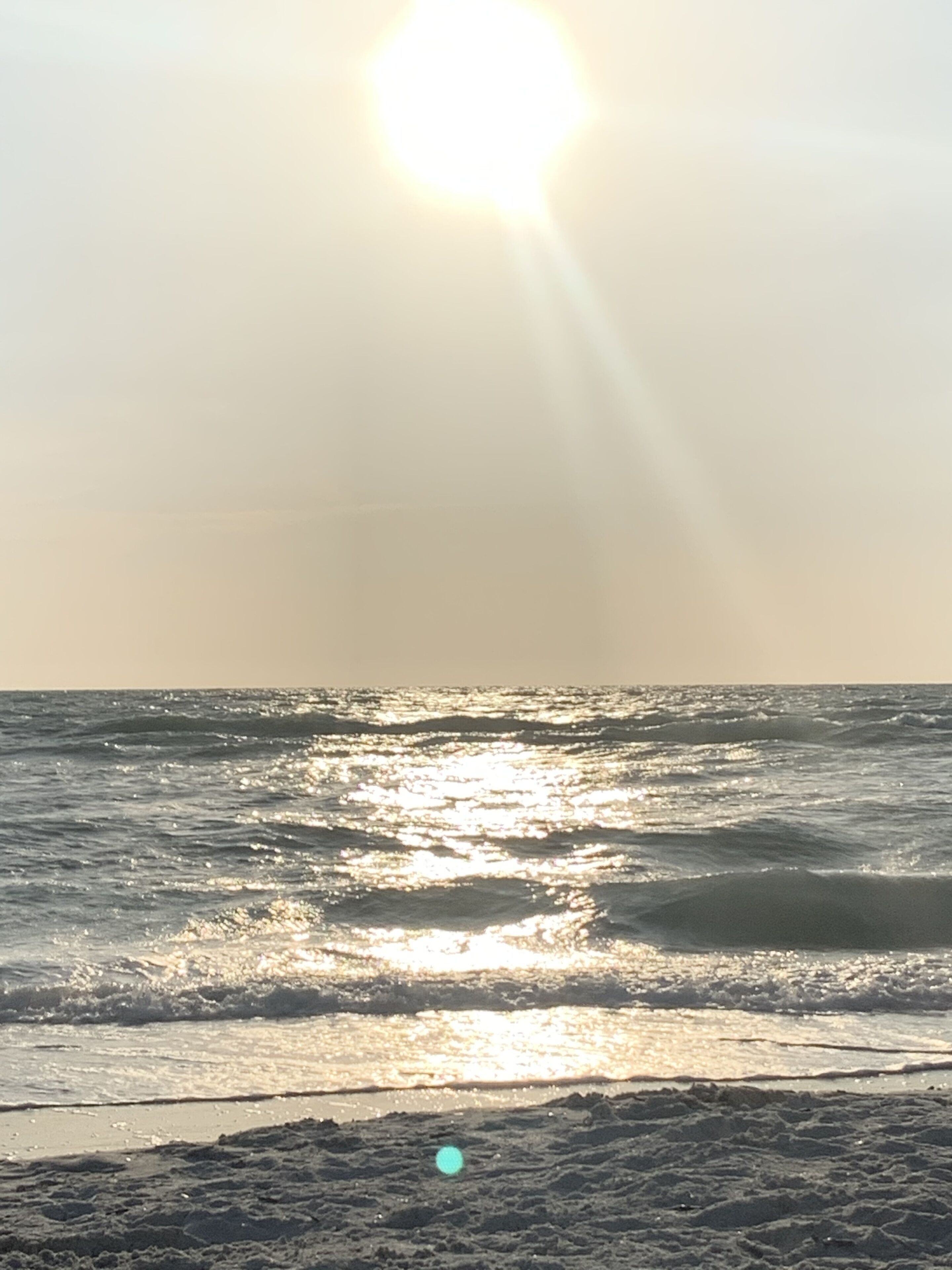 A beach with sunlight reflecting off the water.