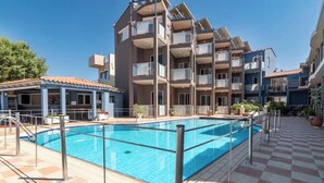 Un edificio de varios pisos con balcones, piscina y un paseo con baldosas.