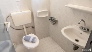 Baño pequeño y limpio con inodoro, lavamanos y toallero.