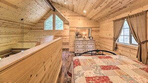 Une chambre dans une cabane en bois, avec un lit, une commode et une fenêtre donnant sur la forêt.