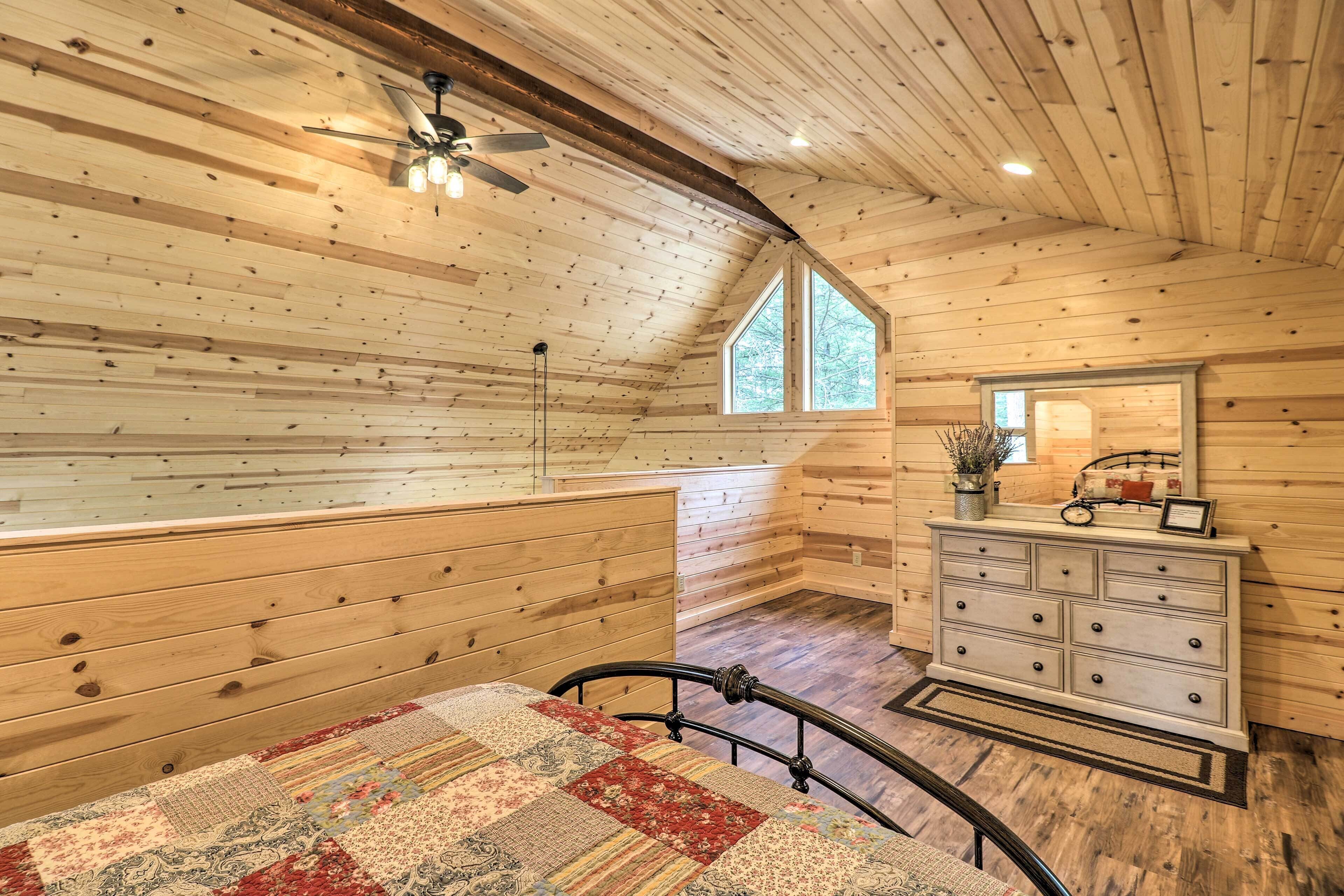 A wooden cabin bedroom with a bed, dresser, and a window.