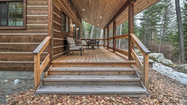 Une cabane en bois avec une véranda couverte, des marches menant à l’entrée et une table avec des chaises sur la véranda.