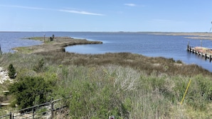 Un paysage côtier avec un ciel dégagé, une étendue d’eau et une jetée qui s’avance dans l’eau.