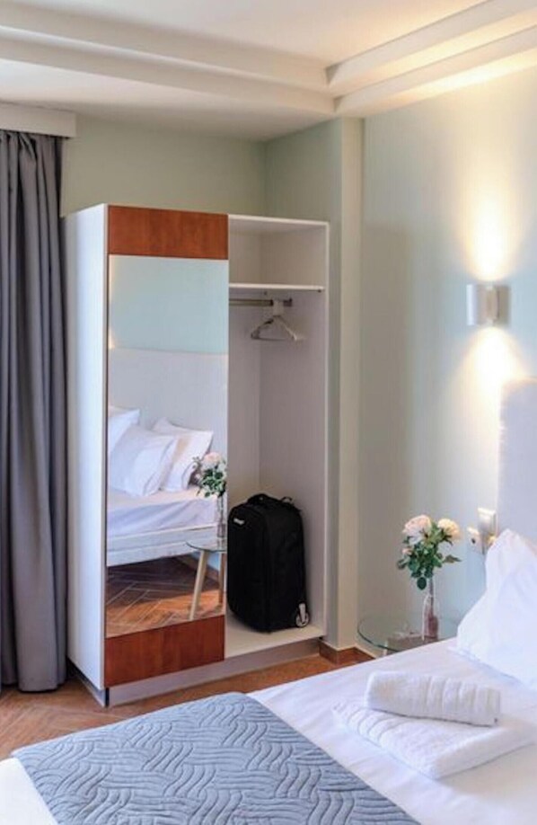 A hotel room with a bed, a wardrobe, a hanging closet, a bedside table with a lamp, and a small potted plant. - "room in Guest Room - Girogiali Beach Hotel" (Chania)