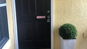 Een zwarte deur met een 'ROKEN VERBODEN'-bord, een brievenbus en een 'hello'-mat.