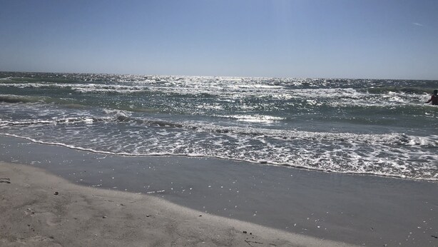 Een strand met golven en een heldere lucht.