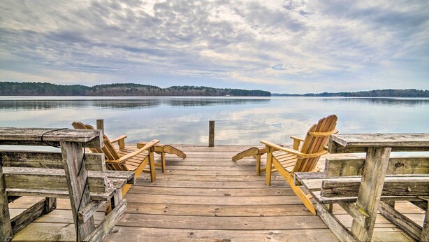A wooden dock with two wooden chairs facing a calm lake, surrounded by trees. - Authentic Retreat w/ Private Dock on Coosa River! (Shelby)