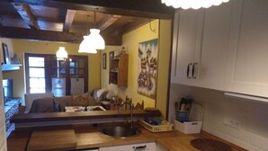 A compact kitchen with a dishwasher, a sink, and a stove. There is a wooden countertop and a mirror reflecting the kitchen.