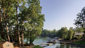Une zone herbeuse avec une jetée qui s’avance dans un lac, entourée d’arbres et d’un petit bâtiment.