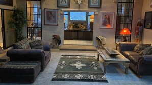 A cozy living room with a fireplace, comfortable seating, and artwork on the walls. - A COWBOYS CASA--BEST RED ROCK VIEWS IN SEDONA -WALK TO TLAQUEPAQUE & UPTOWN-- (Sedona)