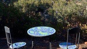 A patio with two round tables and chairs, overlooking a mountainous landscape with sparse vegetation and a clear sky. - A COWBOYS CASA--BEST RED ROCK VIEWS IN SEDONA -WALK TO TLAQUEPAQUE & UPTOWN-- (Sedona)