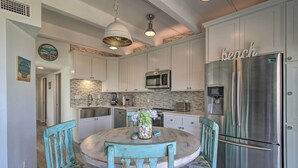 Una cocina con armarios blancos, un refrigerador de acero inoxidable y una mesa redonda con sillas.