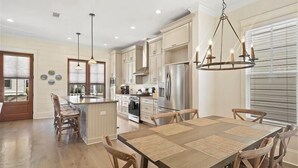 Een moderne keuken met roestvrijstalen apparatuur, een centraal kookeiland en hanglampen.