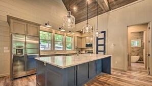 A modern kitchen with a large island, stainless steel appliances, and wooden flooring. - Perfect for Couples,2 King Master bedrooms, Dry Sauna, Hot Tub, 3 covered decks (Broken Bow)