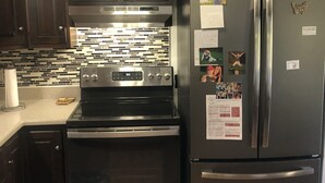 A kitchen with dark wooden cabinets, stainless steel appliances including a refrigerator, stove, and oven.
