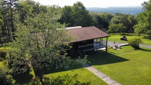 A cabin with a porch, surrounded by a well-maintained lawn and dense forest.