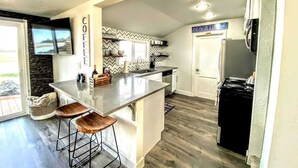 Eine moderne Küche mit einer zentralen Kochinsel, Barhocker, Backofen und Kühlschrank.