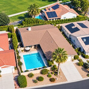 A residential area with a swimming pool, solar panels, and a well-maintained garden. - Private Oasis in With Pool-Spa-Cooling Misters (Palm Desert)