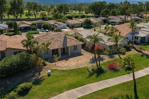 A residential area with houses, palm trees, and a well-maintained lawn.