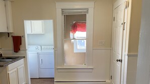 A kitchen with white cabinets, a stove, and a washing machine. - Cute, Convenient and Clean (Wautoma)