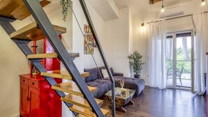 Ein modernes Wohnzimmer mit einer Holztreppe, einem roten Schrank, einem grauen Sofa und einem Glastisch.