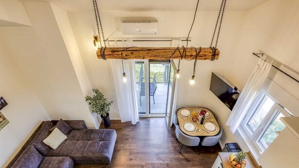 Ein modernes Wohnzimmer mit Sofa, Esstisch und Küchenbereich.
