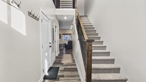 A staircase with a wooden handrail and carpeted steps leading to a landing.