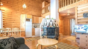 Interior de uma cabana de madeira com sala de jantar, cozinha e sala de estar.