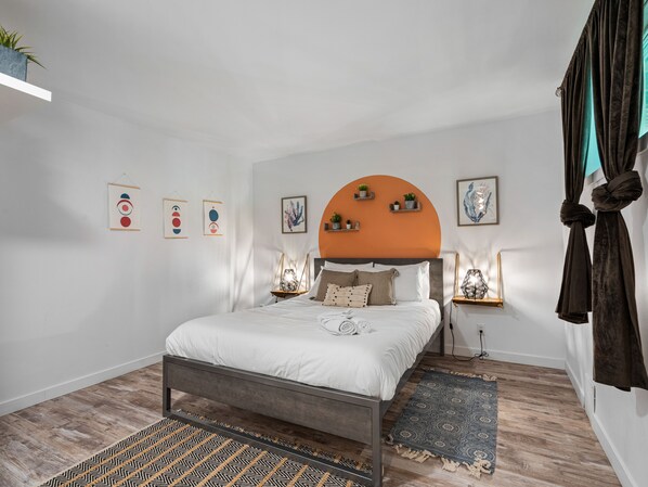 A modern bedroom with a bed, bedside tables, wall art, and a hanging plant. - Le Sommet, 25 min from Tremblant with SPA (Labelle)