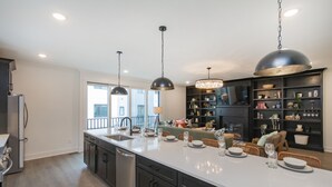 Una cucina moderna con un'ampia isola, mobili scuri e lampade a sospensione.