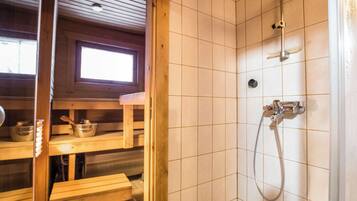 Puuinen mökki, jossa on suihkutila, puiset penkit ja ikkuna.