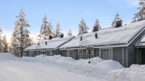 Un lodge imbiancato dalla neve con baite in legno, cielo sereno e strada coperta di neve.