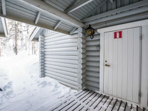 Un edificio de madera cubierto de nieve, con una puerta blanca y un letrero de salida de emergencia rojo.